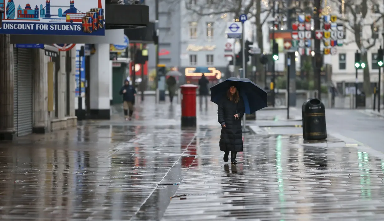Seorang wanita melintas di jalan dekat Leicester Square, London, Inggris, 21 Desember 2020. Pada Minggu (20/12), Menteri Kesehatan Inggris Matt Hancock memperingatkan bahwa galur baru COVID-19 "tidak terkendali" di Inggris. (Xinhua/Han Yan)