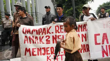 Seorang anak melintas di depan pengunjuk rasa di Kedubes Belanda di Jakarta, Rabu (23/11). Mereka meminta pemerintah Belanda menghentikan upaya mendorong investasi dalam pembangunan infrastruktur di Teluk Jakarta. (Liputan6.com/Helmi Fithriansyah)