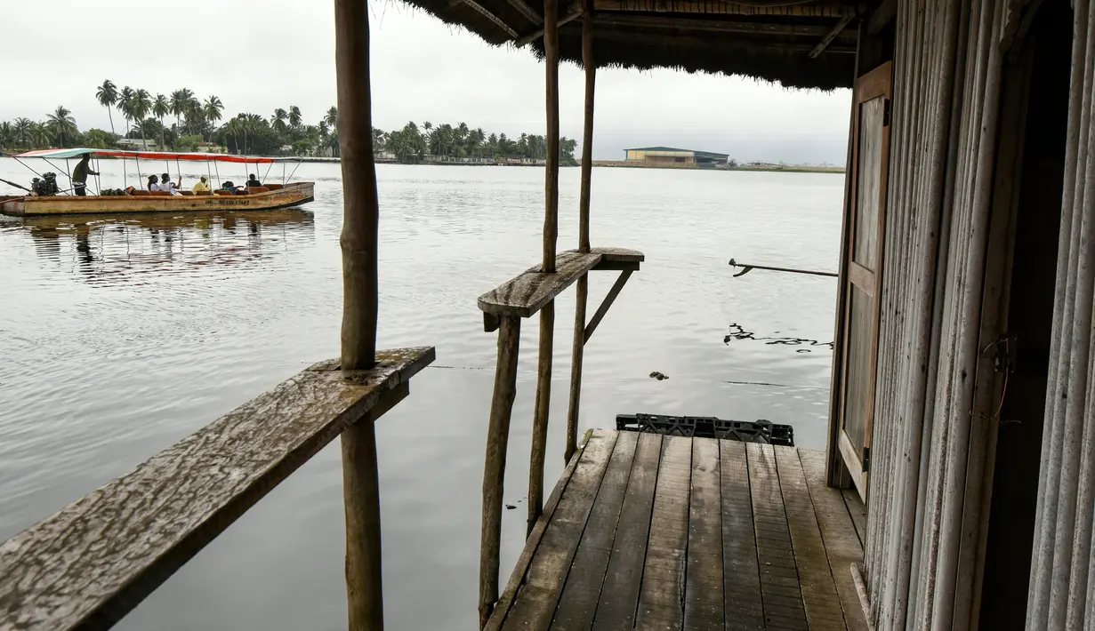 Sebuah kapal penumpang berlayar melewati pulau buatan dari sampah plastik daur ulang di Abidjan, Pantai Gading pada Agustus 2019. Eric Becker asal Prancis membangun sebuah pulau terapung dari sekitar 700.000 sampah plastik daur ulang yang dikumpulkan di daerah sekitarnya. (ISSOUF SANOGO/AFP)