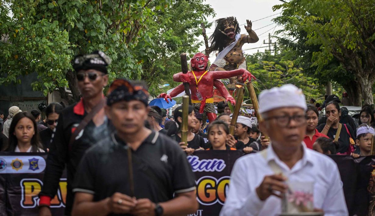 Acara ini berlangsung meriah melibatkan arak-arakan patung raksasa sebagai simbol pembersihan unsur negatif, serta menampilkan perpaduan budaya Bali dan ikon khas Surabaya. Tampak dalam foto, seorang penganut Hindu membawa Ogoh-ogoh, patung yang melambangkan roh jahat, selama pawai menjelang Nyepi di Surabaya pada Rabu 18 Maret 2026. (JUNI KRISWANTO/AFP)