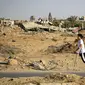 Seorang anak Palestina yang kakinya diamputasi berjalan di sepanjang jalan, melewati bangunan-bangunan yang hancur selama pemboman Israel, di kamp pengungsi al-Bureij di Jalur Gaza tengah pada 24 Juni 2024. (Eyad BABA/AFP)