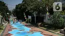 Warga melintas di atas jalan yang telah dilukis mural di Jalan Keuangan, Cilandak, Jakarta, Rabu (26/8/2020). Mural di sepanjang jalan Keuangan menuju museum Basoeki Abdullah itu bertujuan memperindah wilayah tersebut serta sebagai ajang promosi museum. (Liputan6.com/Faizal Fanani)