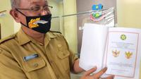 Kepala Kesbangpol Garut Wahyudijaya, menunjukan perubahan posisi dan komposisi burung garuda dalam  lembang negara Garuda Pancasila. (Liputan6.com/Jayadi Supriadin)