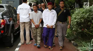 Petugas membawa dua terduga pelaku persekusi U dan M di Polda Metro Jaya, Jakarta, Jumat (2/6). Reskrim Polres Jaktim menangkap dua pelaku persekusi terhadap PMA, 15 tahun, karena diduga menghina FPI dan Rizieq Syihab. (Liputan6.com/Immanuel Antonius)