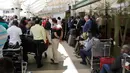 Penumpang yang terdampar menunggu penerbangan mereka setelah aksi mogok kerja di bandara JKIA, Nairobi, Rabu (6/3). Petugas pemadam meninggalkan landasan pacu, pegawai keamanan, staf check in, dan staf bagasi juga berhenti bekerja (AP Photo/Khalil Senosi)