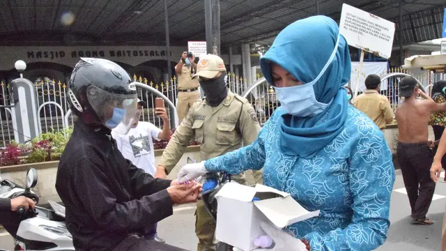 Bupati Banyumas, Achmad Husein dan Ketua Tim Penggerak PKK Banyumas membagikan hand sanitizer berbahan baku ciu dan masker gratis untuk masyarakat. (Foto: Liputan6.com/Humas Pemkab Banyumas/Muhamad Ridlo)