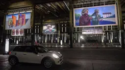 Orang-orang mengunjungi pameran seni dengan mengendarai mobil mereka melintasi gudang yang memajang lukisan dan foto di Sao Paulo pada 30 Juli 2020. Dengan galeri-galeri dan museum ditutup akibat pandemi virus corona, pemilik galeri seni Brasil meresmikan pameran drive-thru. (NELSON ALMEIDA/AFP)