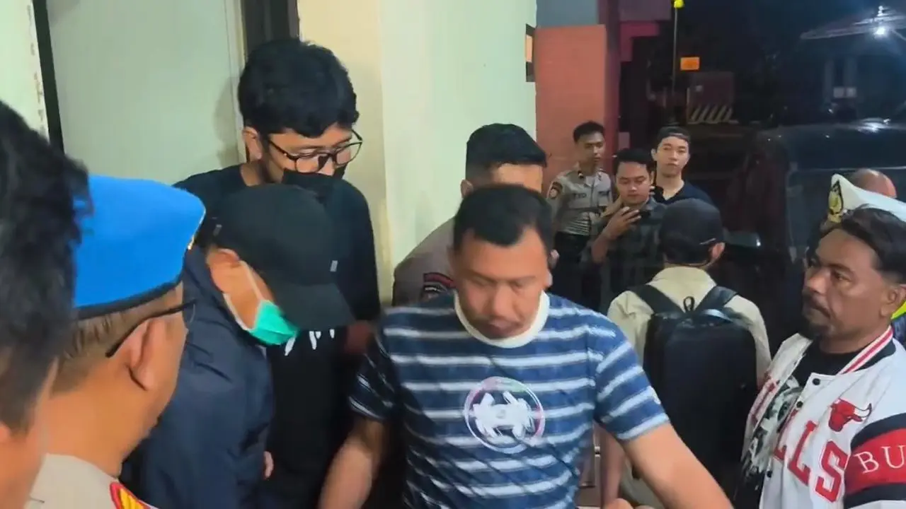 Bupati Sudewo berjaket biru, bertopi hitam dengan memakai masker dinaikan ke mobil dengan kawalan ketat aparat Polres Kudus