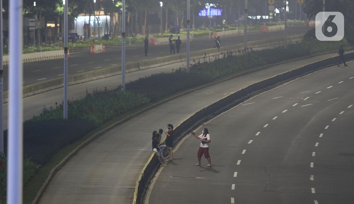 Warga berada di jalan lengang kawasan Sudirman, Jakarta, Rabu (12/5/2021) malam. Polda Metro Jaya memberlakukan crowd free night untuk mencegah kerumunan takbir keliling di malam Idul Fitri 1442 yang berlaku mulai pukul 22:00 malam ini. (Liputan6.com/Herman Zakharia)