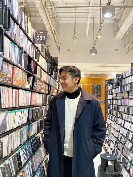 Di sini terlihat Jerome Polin menumpuk 3 jenis outfit. Untuk innerwear, ia tampak mengenakan turtleneck, yang ditumpuknya dengan sweater putih polos, ditambah long coat biru navy sebagai outerwear.