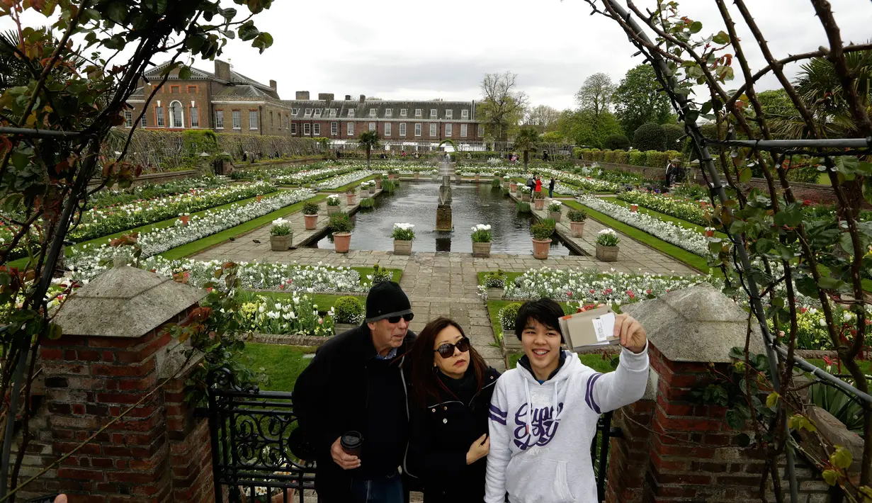 Pengunjung berpose di The White Garden, London, Kamis (13/4). The White Garden dibangun sebagai taman peringatan untuk mengenang Putri Diana. (AP Photo / Matt Dunham)