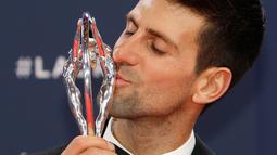 Petenis Serbia, Novak Djokovic mencium trofi seusai meraih penghargaan World Sportsman of the Year dalam ajang Laureus World Sports Awards 2019 di Monako, Senin (18/2). Ini merupakan penghargaan Laureus ke-4 bagi Djokovic. (AP/Claude Paris)