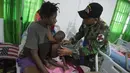 Tim medis dari satuan tugas militer Indonesia memeriksa seorang anak yang sedang menyusu pada ibunya di rumah sakit setempat di Agats, Asmat, provinsi Papua Barat (26/1). (AFP/Bay Ismoyo)
