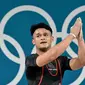 Rizki Juniansyah berhasil mencatat total angkatan 354 kg usai sukses mengangkat beban 155 kg snatch dan 199 kg clean and jerk. (Miguel MEDINA/AFP)