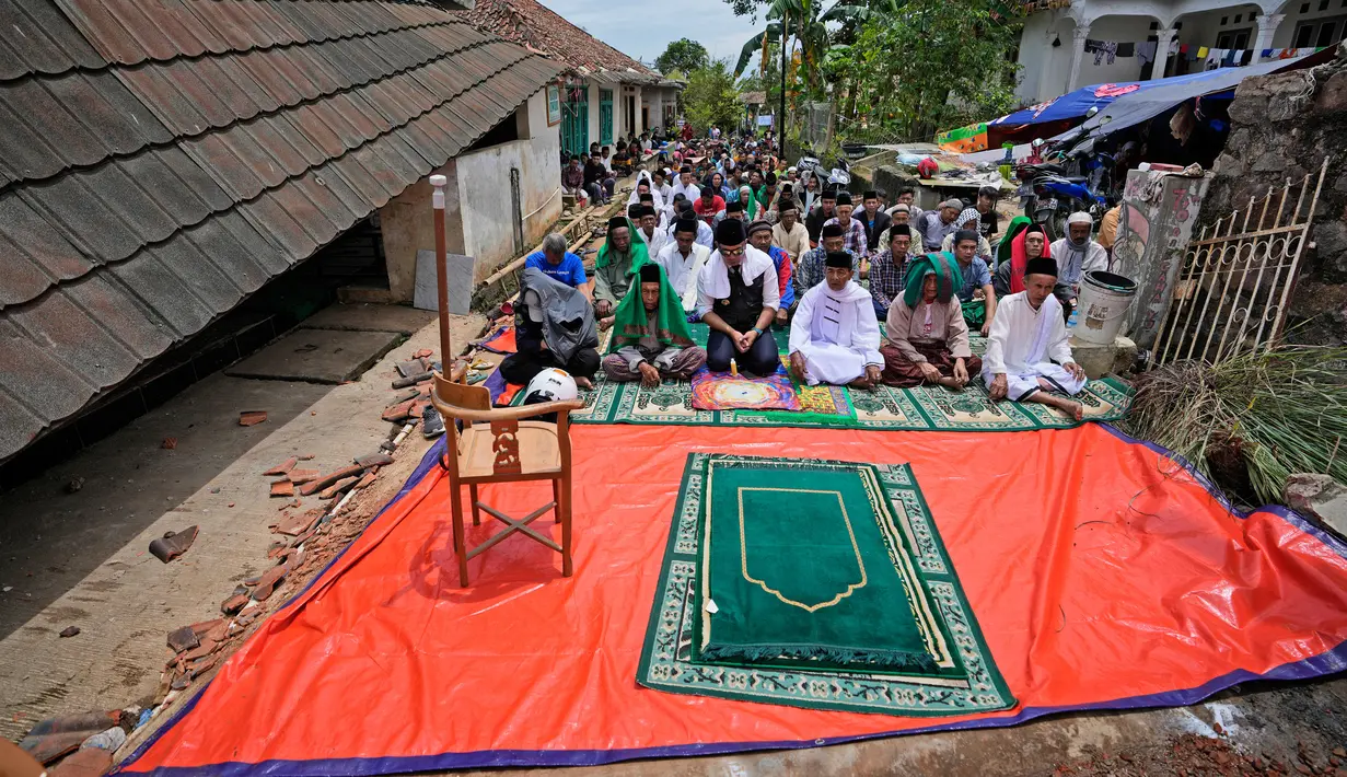 Umat muslim melaksanakan salat Jumat di luar masjid yang rusak parah akibat gempa di Desa Gasol, Cianjur, Jawa Barat, Indonesia, Jumat (25/11/2022). Gempa dengan magnitudo 5,6 yang mengguncang Cianjur pada 21 November 2022 lalu telah menewaskan 272 orang, 2.046 orang luka-luka, dan sebanyak 62.545 orang mengungsi. (AP Photo/Achmad Ibrahim)