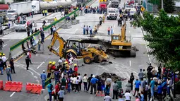 Sebuah lubang menelan mobil yang ditumpangi seorang ayah dan putranya di jalan raya Meksiko-Cuenava, Meksiko, Rabu (12/7). Regu penyelamat membutuhkan waktu delapan jam untuk membuat jalan guna mencapai mobil tersebut. (AP/Tony Rivera)