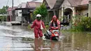 Sejak akhir pekan lalu, Banjir terjadi di sembilan wilayah di Aceh. Tampak dalam foto, seorang pria mendorong sepeda motornya menerobos banjir di jalan yang tergenang setelah hujan deras di permukiman Darul Imarah, pinggiran Banda Aceh, pada Kamis 27 November 2025. (CHAIDEER MAHYUDDIN/AFP)