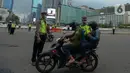 Polisi mengimbau pengguna jalan yang menggunakan kendaraan pribadi mobil dan motor yang berboncengan di Bundaran HI, Jakarta, Jumat (10/4/2020). Penerapan hari pertama PSBB hingga 14 hari kedepan ini dilakukan untuk mencegah penyebaran COVID-19 dan selalu menggunakan masker.(merdeka.com/Imam Buhori)