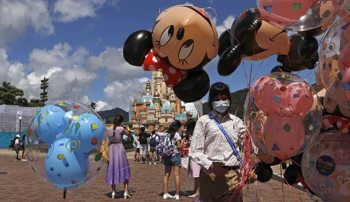 Pegawai yang mengenakan masker untuk mencegah penyebaran COVID-19 menjual balon di Disneyland Hong Kong, Kamis (18/6/2020). Disneyland Hong Kong kembali beroperasi pada 18 Juni 2020 dengan menerapkan sejumlah protokol kesehatan baru. (AP Photo/Kin Cheung)