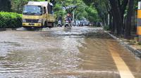 Pengendara melintasi genangan air di Jalan Raya Juanda Kota Depok, Sabtu (20/2/2021). (Liputan6.com/Dicky Agung Prihanto)