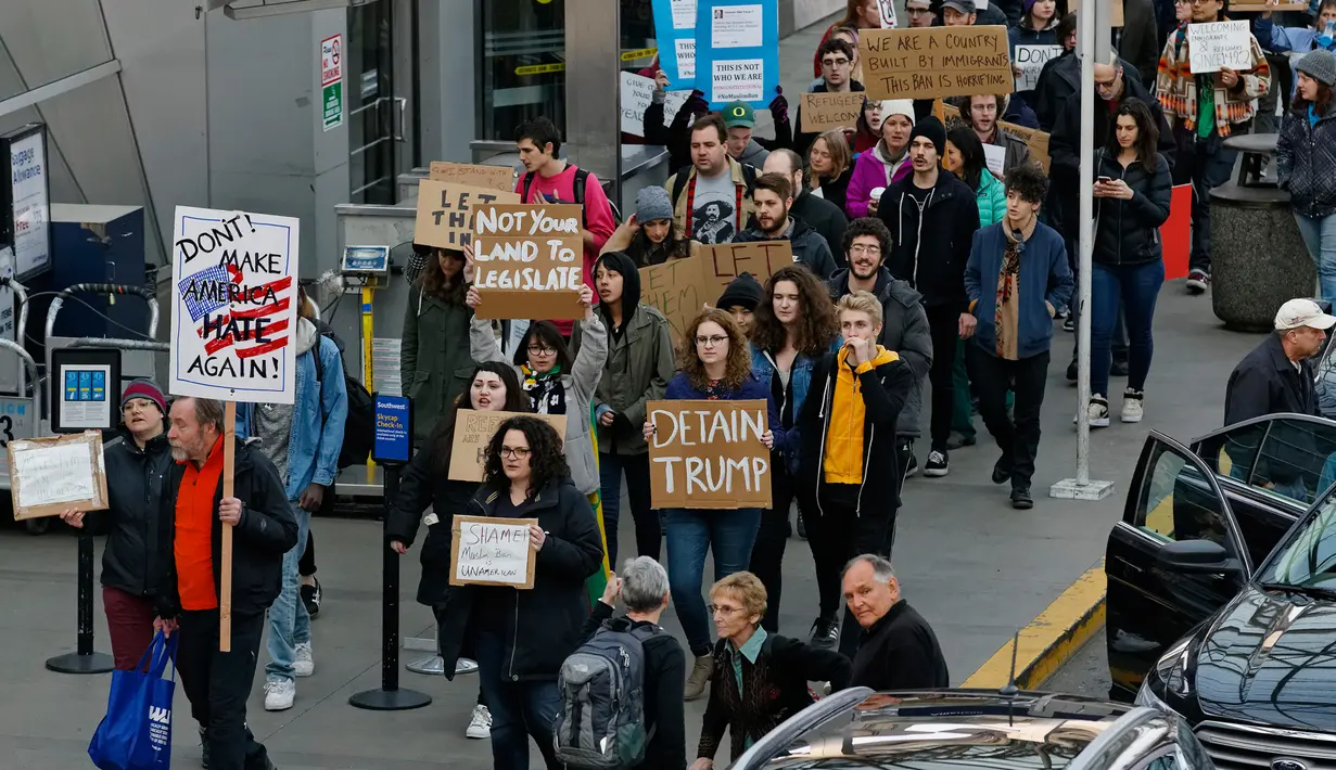 Sejumlah orang menggelar aksi protes di Bandara Internasional Portland, Sabtu (28/1). Massa berkumpul di bandara-bandara AS menolak kebijakan Donald Trump yang melarang warga dari 7 negara muslim masuk ke Amerika Serikat. (Mike Zacchino/The Oregonian/AP)