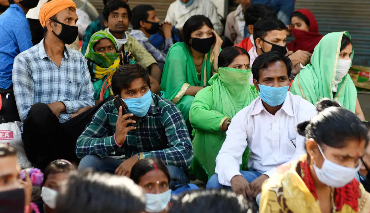 Pekerja migran yang terdampar dan keluarga mereka berkumpul menunggu pemeriksaan medis sebelum pergi dengan kereta api untuk kembali ke kota asal mereka ke Jaunpur, negara bagian Uttar Pradesh, setelah pemerintah melonggarkan lockdown di Amritsar, India, Selasa (19/5/2020). (NARINDER NANU/AFP)