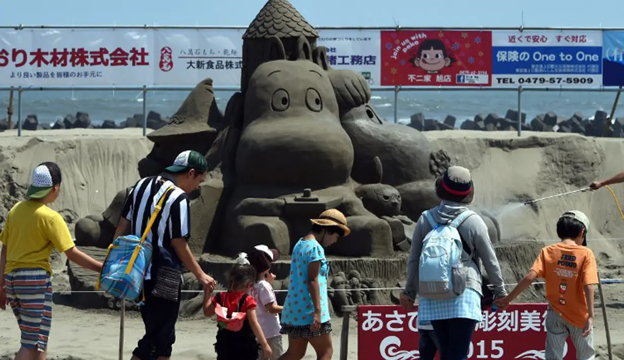 Pengunjung membawa serta keluarga mereka untuk menikmati keindahan seni patung pasir  di pameran Asahi Sand Sculpture, Yasashigaura, pantai Asahi, Tokyo, Sabtu (11/7/2015). Pameran ini digelar mulai Senin (6/7) lalu. (AFP PHOTO/Toshifumi Kitamura)