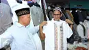 Cawagub DKI Jakarta, Sandiaga S Uno (kanan) mencoba pakaian muslim saat sosialisasi di pasar Blok A dan B Tanah Abang, Jakarta, Senin (26/12). Dihadapan para pedagang, Sandi mensosialisasikan beberapa program andalannya. (Liputan6.com/Helmi Fithriansyah)