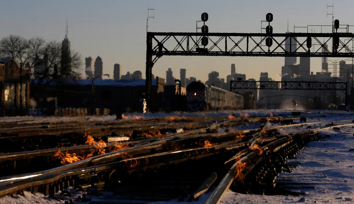 Sistem pemanas berbahan bakar gas menghangatkan lintasan rel kereta di dekat stasiun Metra Western Avenue, Chicago, 29 Januari 2019. Para petugas berupaya membuat kereta komuter tetap beroperasi di tengah suhu udara yang sangat dingin. (AP/Kiichiro Sato)