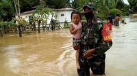 Sertu Ibrahim mengevakuasi balita dari banjir yang melanda Kabupaten Penajam Paser Utara (PPU), Selasa (28/4/2020). (foto: istimiewa)