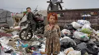 Dua anak berdiri di tumpukan sampah di samping rumah mereka, di Kabul, Afghanistan, Senin, 18 April 2022. (Ebrahim Noroozi/AP Photo)