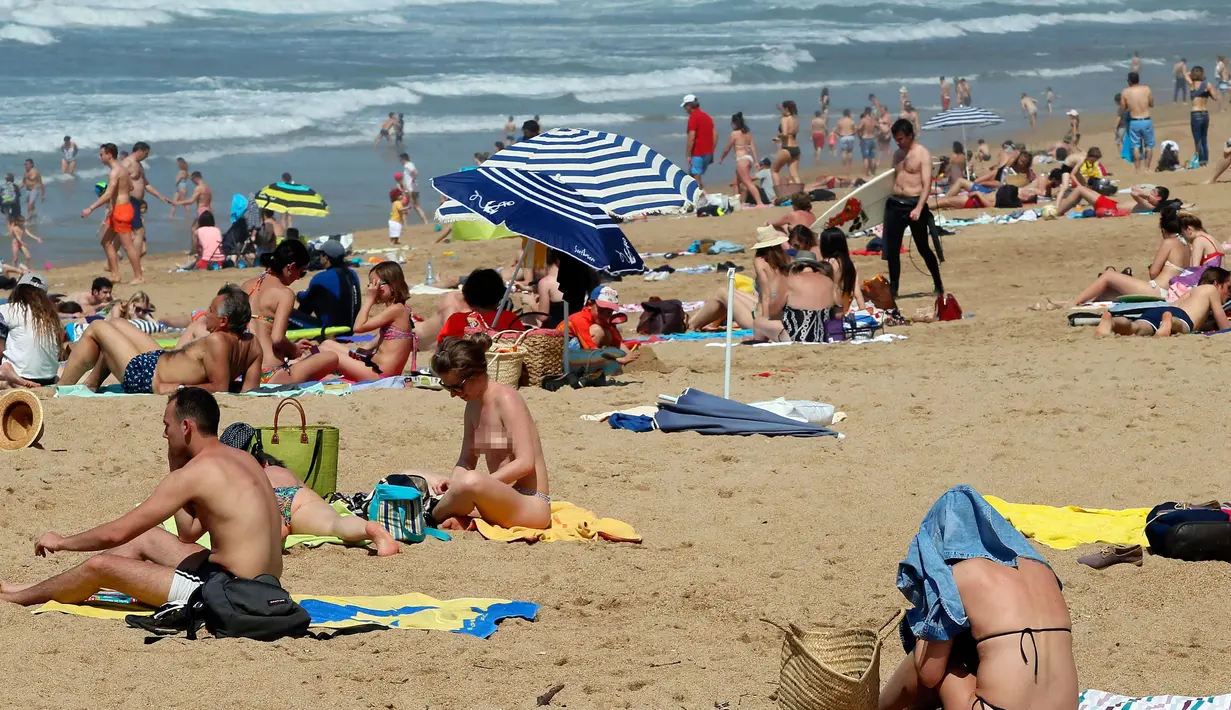 Orang-orang berjemur di pantai Port Vieux, (Old Seaport) di Biarritz, barat daya Prancis, (19/4). Suhu di Prancis barat daya telah mencapai 27 derajat Celcius (80,6 Fahrenheit). (AP Photo / Bob Edme)