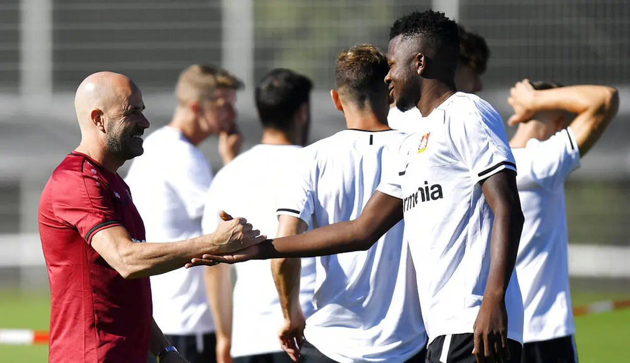 Pelatih Bayer Leverkusen, Peter Bosszduring, berjabat tangan dengan Edmond Tapsoba, usai sesi latihan jelang laga Liga Europa di Leverkusen, Jerman, Selasa (4/8/2020). Bayer Leverkusen akan berhadapan dengan Glasgow Rangers. (AP Photo/Martin Meissner)
