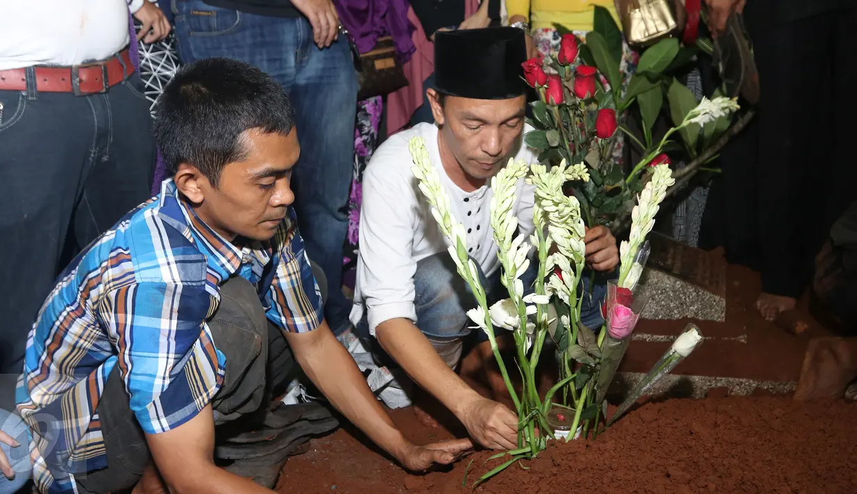 Daus Separo menata bunga di makam Budi Anduk di TPU Kemang, Jati Cempaka, Bekasi, Senin (11/1/2016). Budi Anduk menghembuskan nafas terakhir pada usia 47 tahun di RS Dharmais, Jakarta. (Liputan6.com/Herman Zakharia)