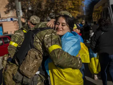 Seorang warga Kherson memeluk anggota pasukan pertahanan Ukraina di Kherson, Ukraina selatan, Senin (14/11/2022). Perebutan kembali Kherson adalah salah satu keberhasilan terbesar Ukraina dalam hampir sembilan bulan sejak invasi Moskow. (AP Photo/Bernat Armangue)