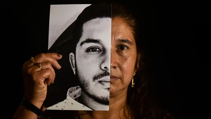 Gladys Betancourth, 51, ibu dari Oscar Obando, 24, satu dari 8 pemuda yang dibunuh dalam pesta di pinggiran Samaniego, Kolombia pada 16 Agustus, berpose dengan foto putranya pada 2 September 2020. Pembunuhan kembali berdarah di pedesaan Kolombia. Korbannya kebanyakan masih muda. (Luis ROBAYO/AFP)