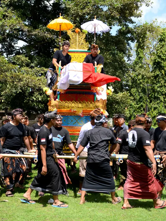 Warga membawa peti mati berisi jenazah Aipda Wayan Sudarsa, polisi korban pembunuhan pasangan bule, di Jimbaran, Bali, Minggu (21/8). Warga Desa Adat Jimbaran dan pecalang pun turut serta mengantarkan korban yang akan diaben. (SONNY Tumbelaka/AFP)