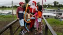 Relawan Jorge Alberto Barrozo, yang mengenakan kostum Sinterklas, berbicara dengan anak-anak saat tiba untuk mengantarkan hadiah di komunitas tepi sungai di daerah pedesaan Careiro da Varzea, negara bagian Amazonas, Brasil pada Sabtu 20 Desember 2025. (Michael DANTAS/AFP)
