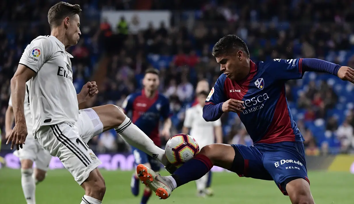 Gelandang Real Madrid, Marcos Llorente, berebut bola dengan striker Huesca, Cucho Hernandez, pada laga La Liga Spanyol di Stadion Santiago Bernabeu, Madrid, Minggu (31/3). Madrid menang 3-2 atas Huesca. (AFP/Javier Soriano)