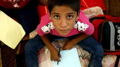  Ekspresi seorang anak pengungsi saat mengikuti kegiatan belajar di sebuah kamp di Ain Issa, Suriah (22/8). Meski belajar di dalam tenda pengungsian, anak-anak tetap antusias mengikuti hari pertama tahun ajaran baru sekolah. (AFP Photo/Delil souleiman)