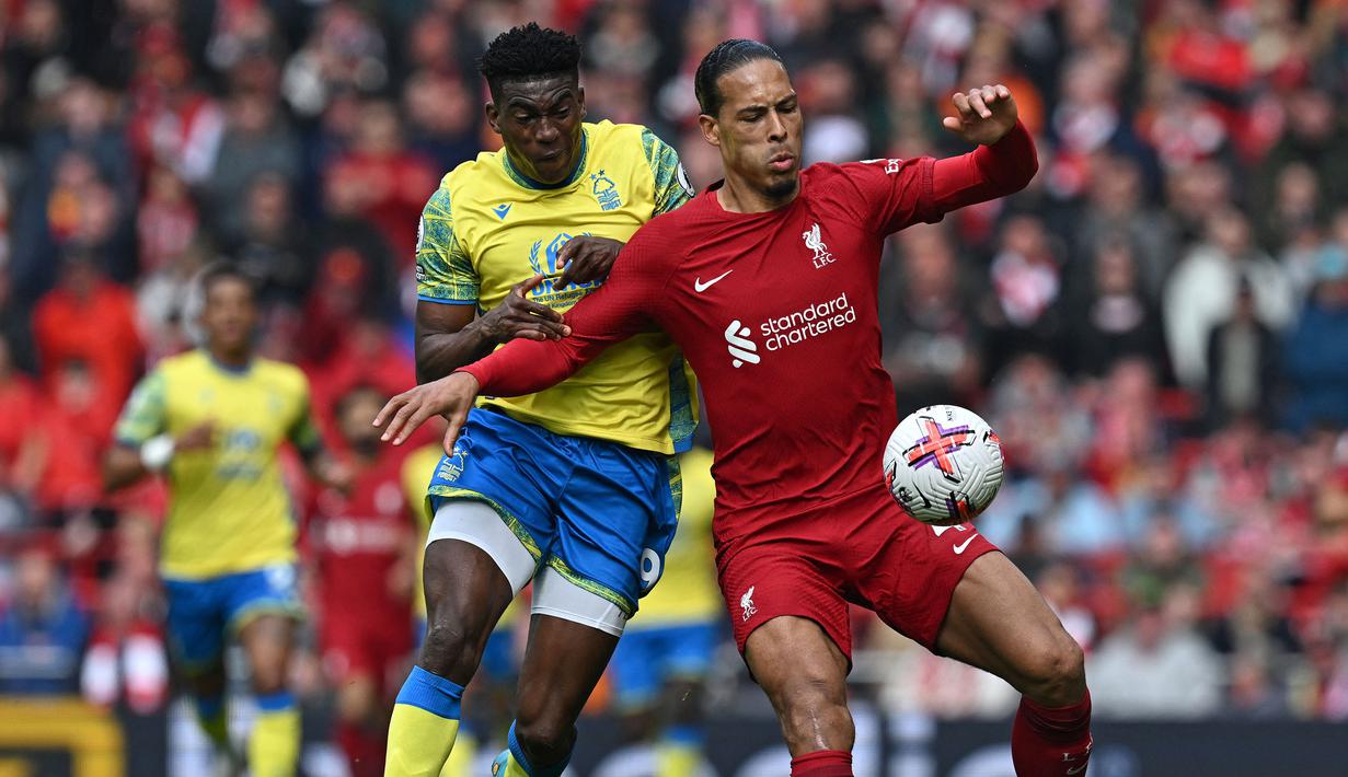 Pemain Liverpool, Virgil van Dijk (kanan) berebut bola dengan pemain Nottingham Forest, Taiwo Awoniyi pada laga pekan ke-32 Liga Inggris 2022/2023 di Anfield, Liverpool, Sabtu (22/04/2023) WIB. The Reds berhasil menang dengan skor 3-2. (AFP/Paul Ellis)