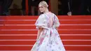 Elle Fanning menaiki tangga karpet merah saat tiba menghadiri screening film "Les Miserables" dalam acara Festival Film Cannes ke-72 di Prancis (15/5/2019). Aktris 21 tahun ini tampil cantik mengenakan gaun taman haute couture karya Valentino. (AP Photo/Arthur Mola)