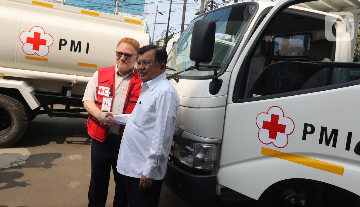 Ketua Umum PMI, Jusuf Kalla secara simbolis menerima kendaraan bantuan dari Kepala IFRC Perwakilan Indonesia-Timor Leste dan ASEAN, Jan Gelfand di Markas PMI Pusat, Jumat (17/1/2020). IFRC menyerahkan bantuan berupa 10 unit truk tangki air dan satu truk barang. (Liputan6.com/Herman Zakharia)