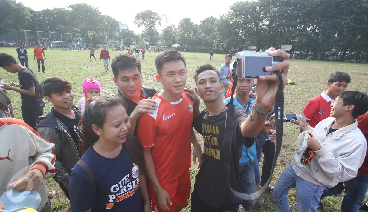Pendukung klub Persija Jakarta, The Jakmania berfoto bersama pemain seusai sesi latihan di Lapangan Banteng, Jakarta, Selasa (11/4). Ratusan The Jakmania datang untuk menonton dan menyapa para pemain. (Liputan6.com/Immanuel Antonius)
