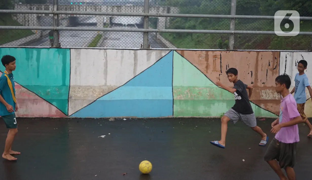 Anak-anak bermain sepak bola di sekitar kawasan Depok, Jawa Barat, Kamis (16/4/2020). Kurangnya sanksi tegas membuat sebagian warga Depok bebas berkeliaran untuk bersosialisasi, meskipun saat ini sedang diberlakukan PSBB untuk mencegah penyebaran Covid-19. (Liputan6.com/Immanuel Antonius)