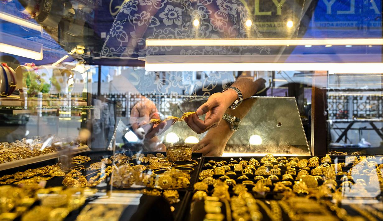 Harga emas Antam lebih mahal Rp 13.000 menjadi Rp 2.665.000 per gram. Tampak dalam foto, seorang karyawan memegang beberapa perhiasan emas di sebuah toko perhiasan di Banda Aceh pada Rabu 14 Januari 2026. (CHAIDEER MAHYUDDIN/AFP)