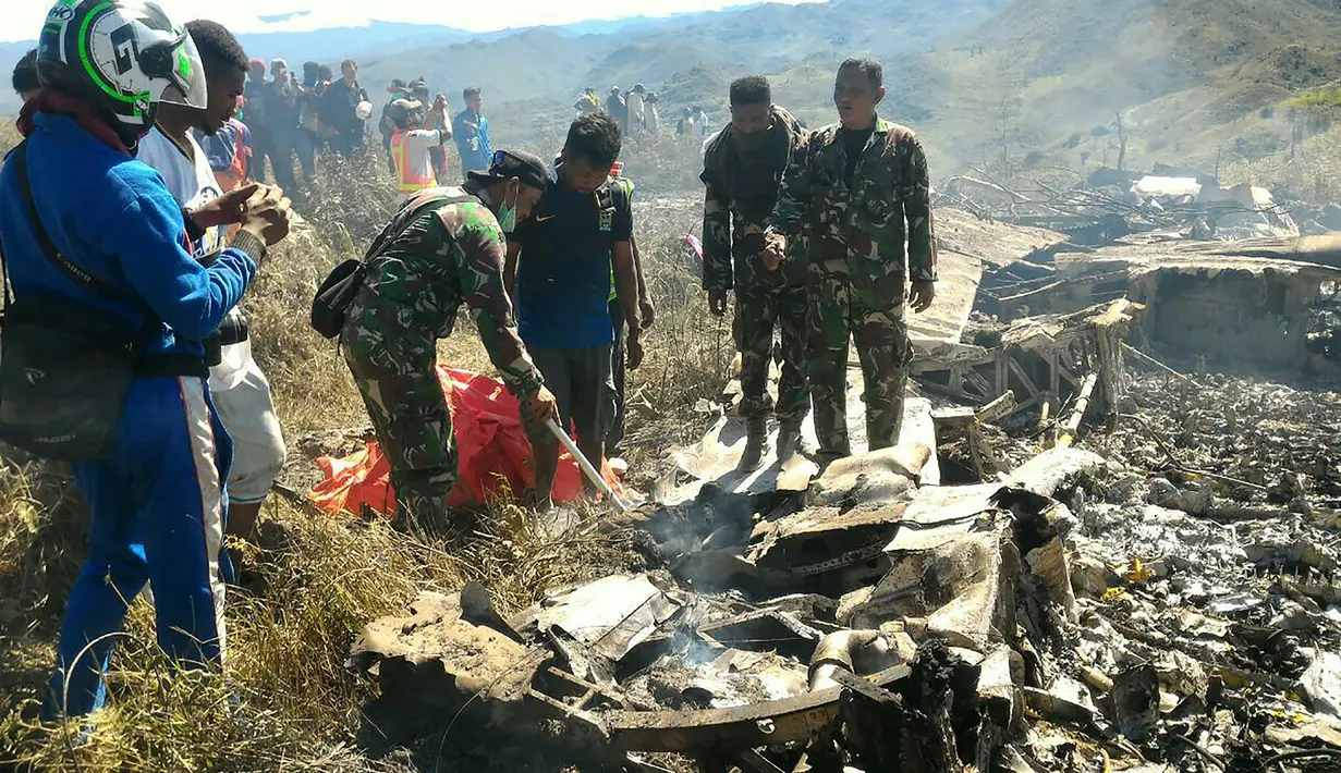 Tentara memeriksa puing dari pesawat Hercules TNI AU yang jatuh di kawasan Wamena, Papua, Minggu (18/12). Pesawat jenis C-130 HS A-1334 itu diduga jatuh menabrak Gunung Tugima sesaat akan mendarat di Bandara Wamena. (HANDOUT/SEARCH AND RESCUE TEAM/AFP)