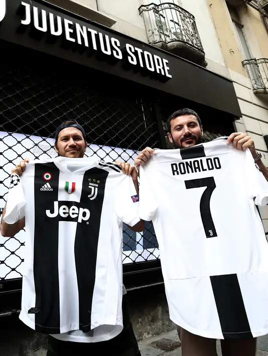 Suporter memperlihatkan jersey Juventus atas nama Cristiano Ronaldo di depan toko resmi klub di Turin, Selasa (10/7). Ronaldo akan diperkenalkan secara resmi ke publik sebagai pemain Juventus pada Senin depan. (AFP PHOTO / Isabella Bonottovv)