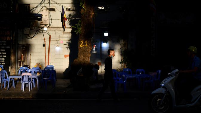 Seorang penjual menunggu pelanggan di luar restoran di sepanjang jalan di Hanoi, ibu kota Vietnam pada 11 Agustus 2020. Setelah mencatat nol kasus COVID-19 selama lebih dari tiga bulan, Vietnam melaporkan sejumlah infeksi baru di dalam negeri sejak akhir Juli. (MANAN VATSYAYANA/AFP)
