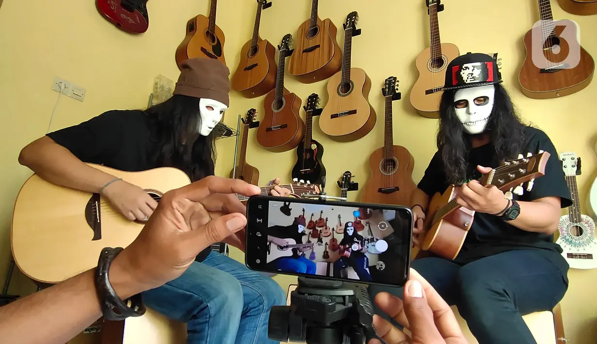 Pemilik showroom dan bengkel Gitar "music666", Ridwan dan Rudi mendemonstrasikan gitar yang akan dijual secara daring di Ciledug, Tangerang, Rabu (22/7/2020). Pemerintah menargetkan 10 juta usaha mikro kecil menengah (UMKM) pada tahun ini terhubung dengan platform digital (Liputan6.com/Angga Yuniar)